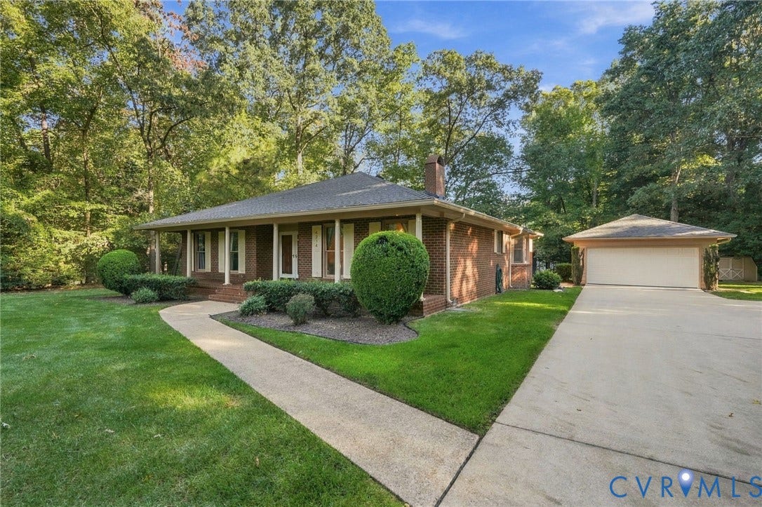 Brick exterior with a covered porch, an attached garage, a concrete driveway, and a pathway