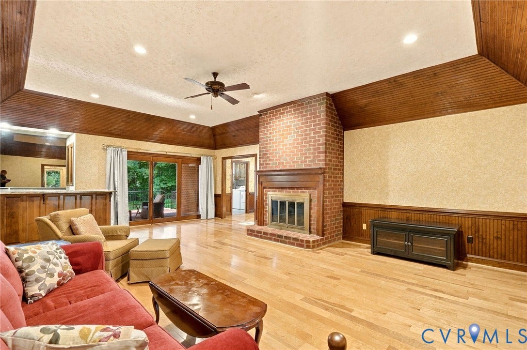 Wood-finish flooring with a brick fireplace, built-in cabinetry, and a sliding glass door