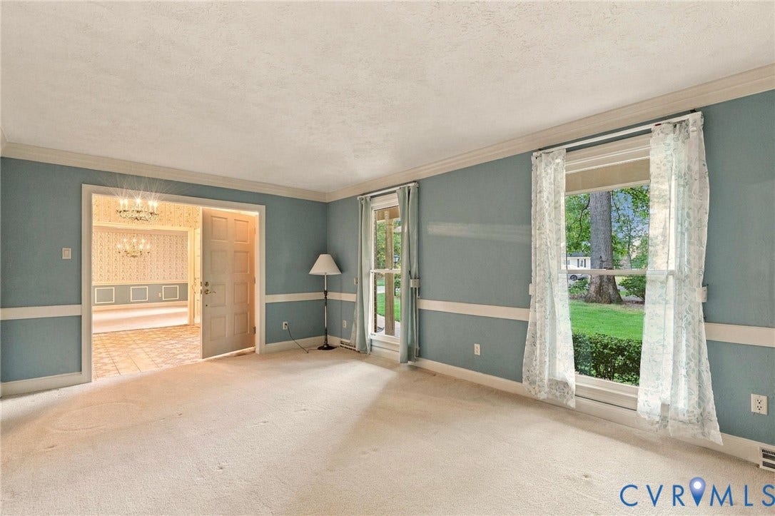 Carpeted room with double-hung windows, crown molding, and wainscoting