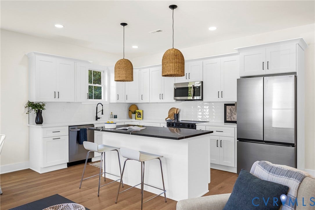 White shaker cabinetry with dark hardware, stainless steel appliances, central island with dark countertop, white subway tile backsplash, and wood-finish flooring