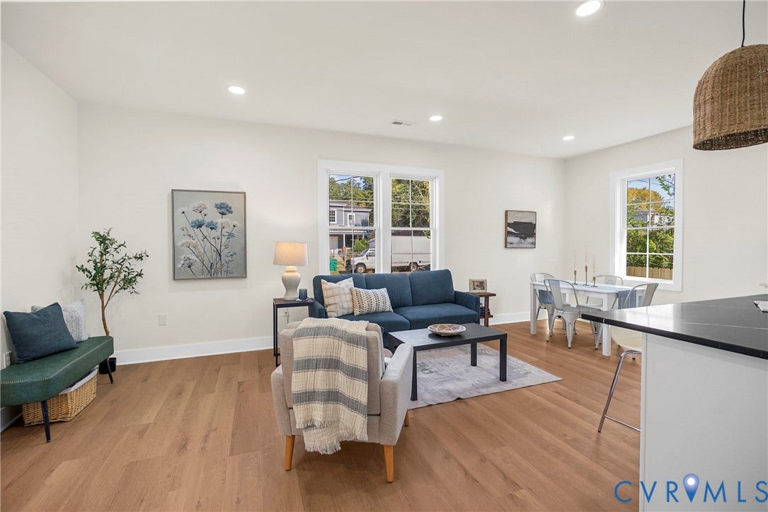 Open-concept living area with wood-finish flooring, recessed lighting, and multiple windows