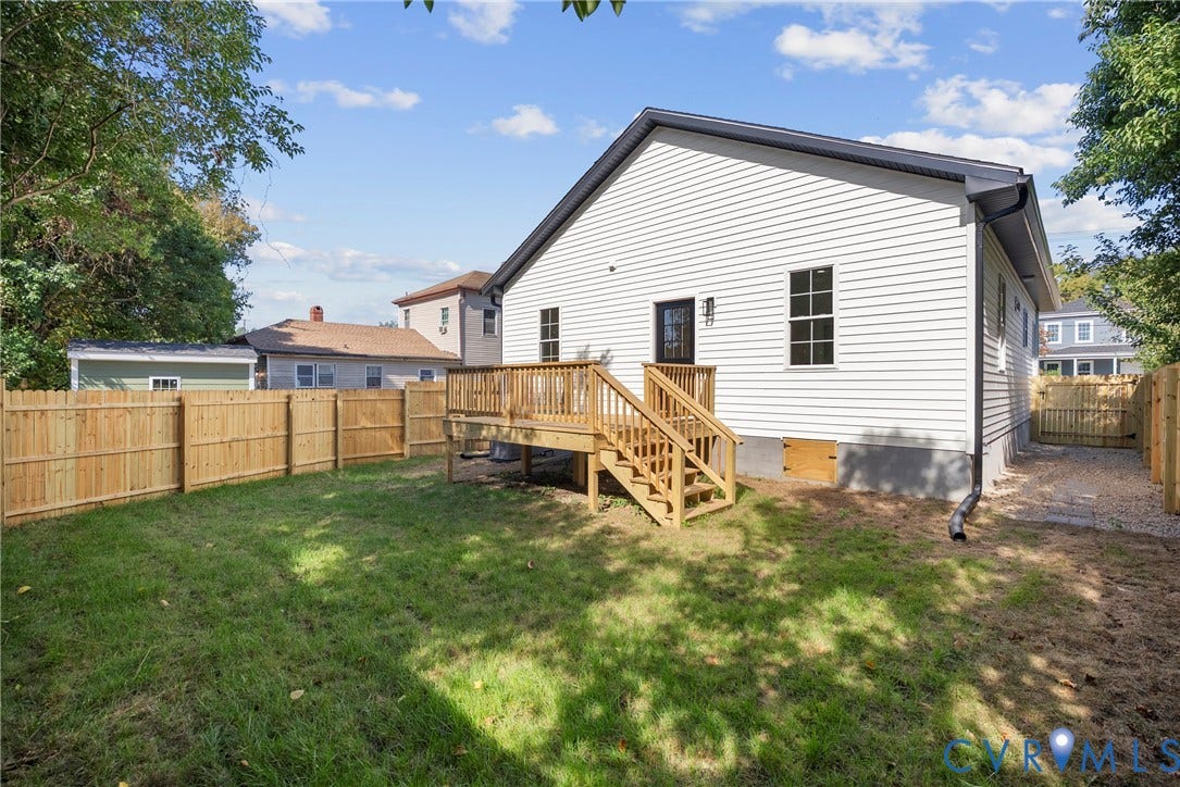 Expansive backyard featuring a new wooden privacy fence, a newly constructed wooden deck, and a gravel walkway