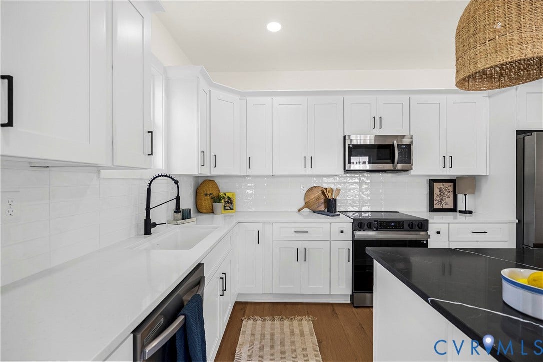 White shaker cabinetry, stainless steel appliances, solid surface countertops, wood-finish flooring, and a white subway tile backsplash