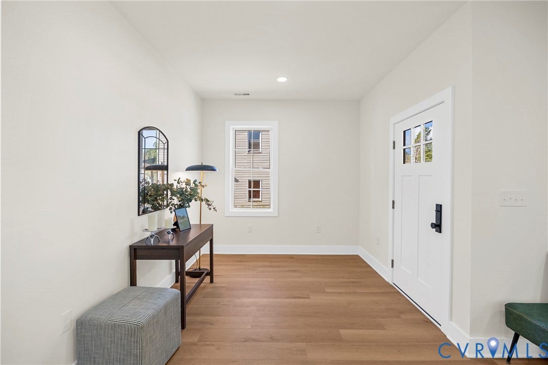 Entryway featuring wood-finish flooring, a white paneled entry door with black hardware, a multi-pane window, and recessed lighting