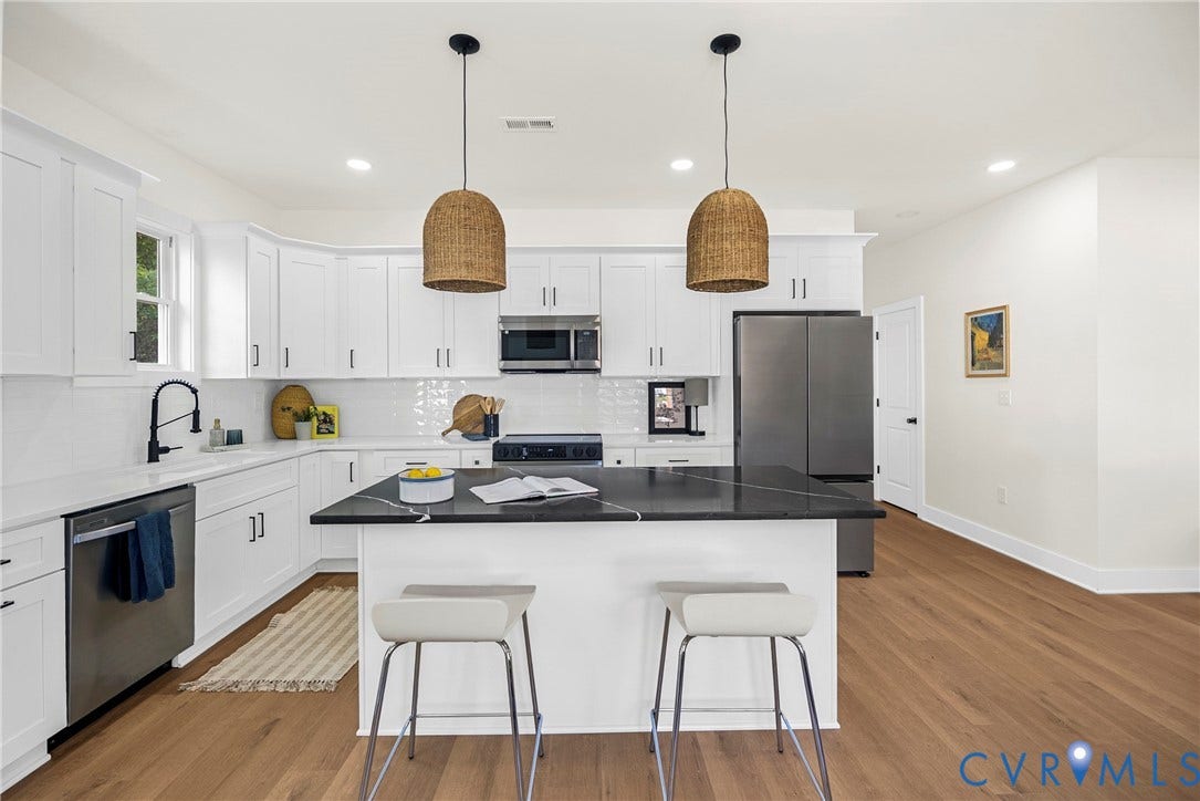 Kitchen featuring white shaker cabinetry, stainless steel appliances, a center island with contrasting countertop, and wood-finish flooring