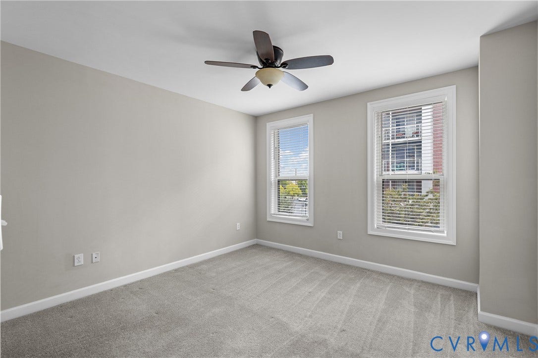 4820 Old Main Street, #301, Henrico, VA 23231 Neutral-toned walls with light gray carpeting, two windows with white trim, and a ceiling fan with integrated lighting
