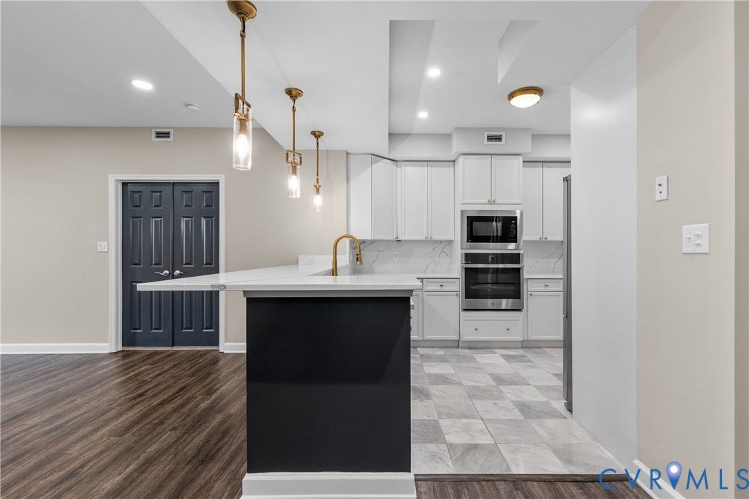 4820 Old Main Street, #301, Henrico, VA 23231 Kitchen featuring light grey cabinetry, built-in stainless steel appliances, a brass-finish faucet, and a large central breakfast bar with quartz countertop.