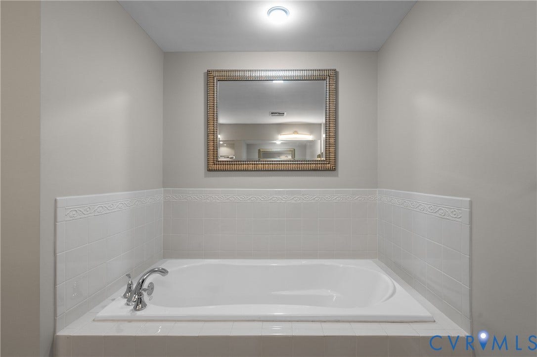 4820 Old Main Street, #301, Henrico, VA 23231 Built-in sunken soaking tub with a polished chrome faucet, surrounded by white tile featuring a decorative border.