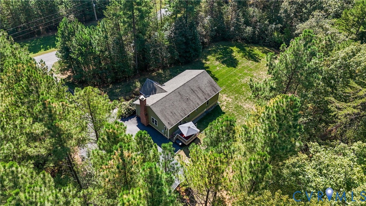 700 Manchester Road, Louisa, VA 23024 Spacious property surrounded by mature trees, featuring a gabled roof, a brick chimney, and a visible deck