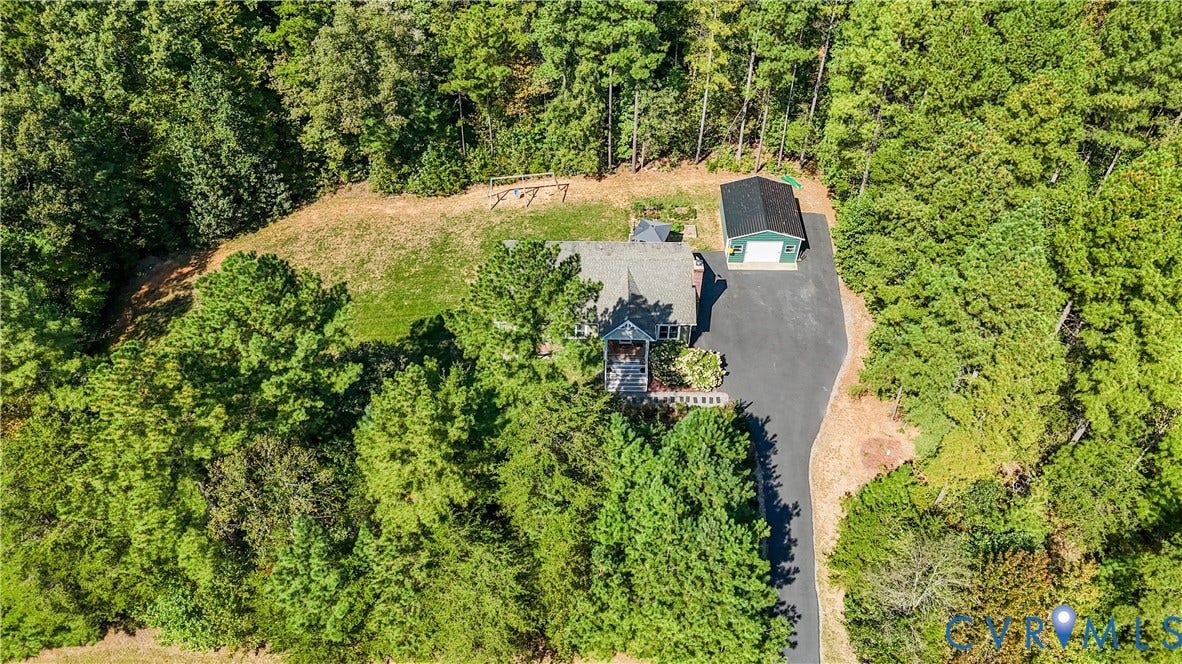700 Manchester Road, Louisa, VA 23024 Wooded lot with asphalt driveway, featuring a main residence and a detached garage with a dark shingle roof