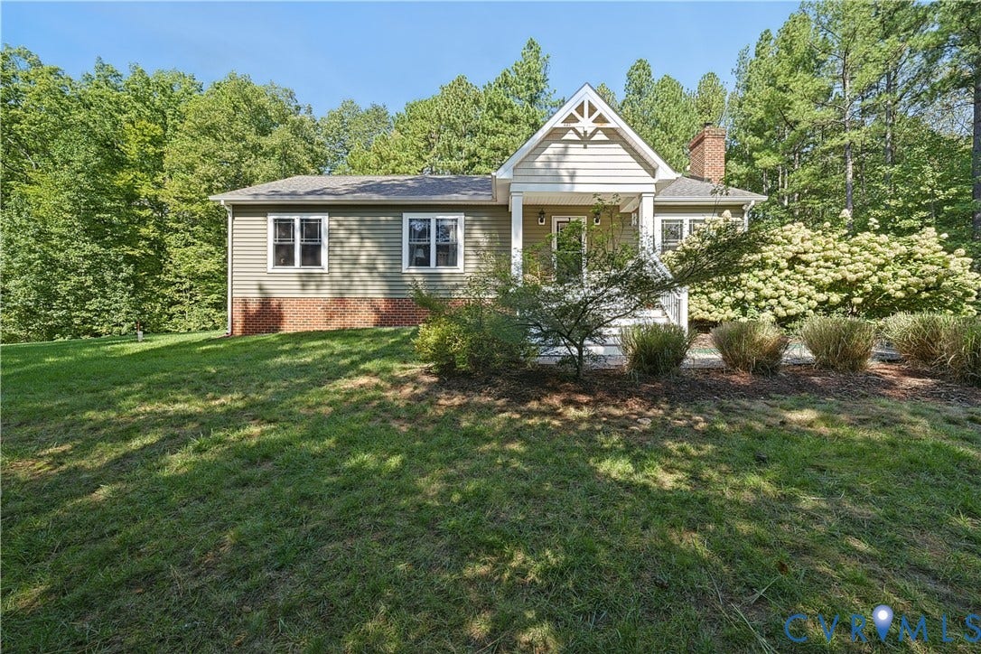 700 Manchester Road, Louisa, VA 23024 Front exterior with green siding, a gable roof entry, brick foundation accents, a prominent brick chimney, and surrounding mature trees