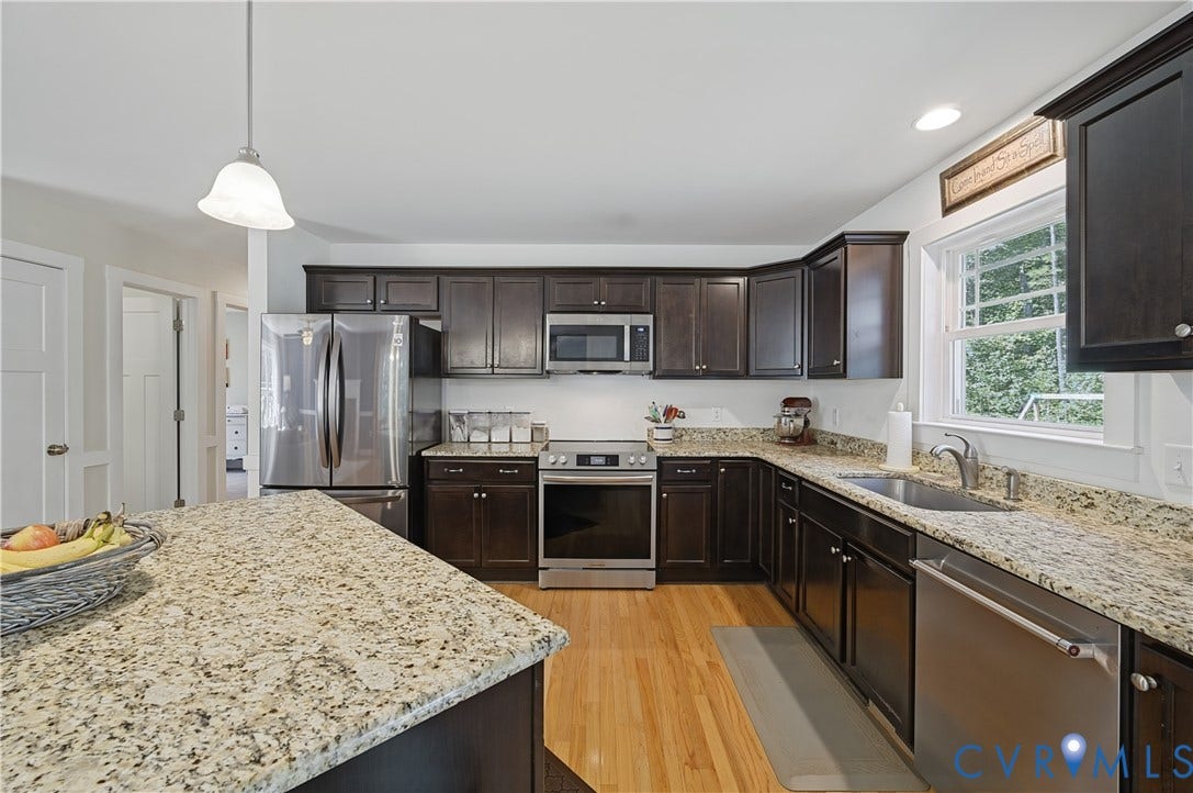 700 Manchester Road, Louisa, VA 23024 Kitchen featuring dark wood cabinetry, light granite countertops, stainless steel appliances, wood-finish flooring, and a white subway tile backsplash