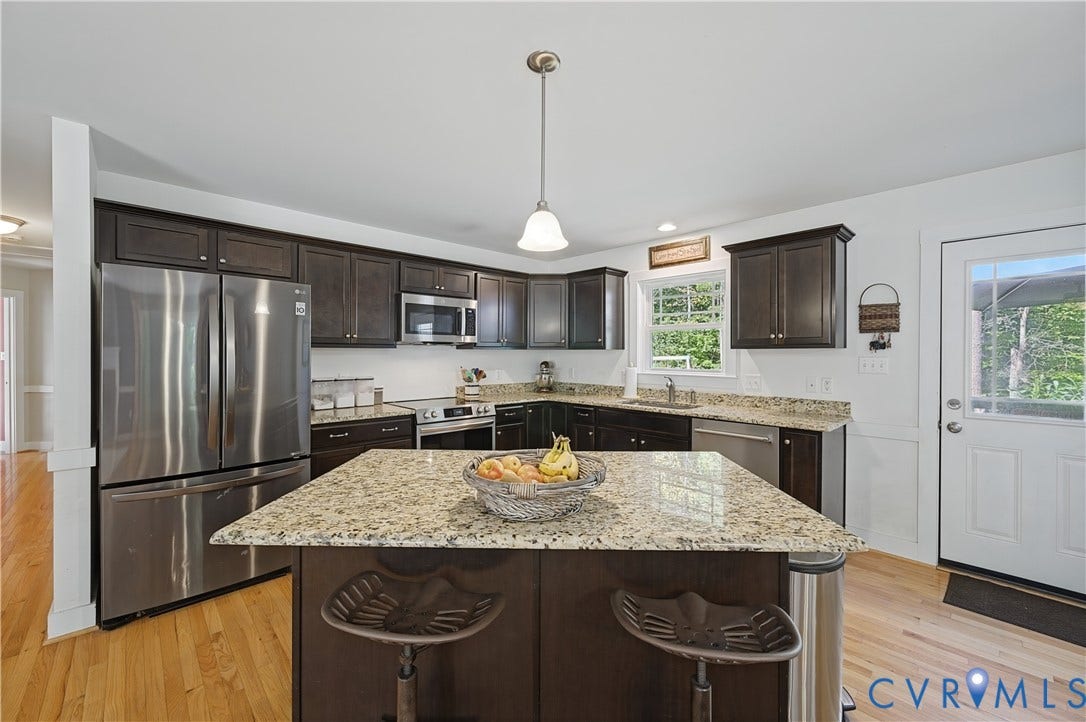 700 Manchester Road, Louisa, VA 23024 Kitchen featuring rich wood cabinetry, stainless steel appliances, granite countertops, a center island with seating, and wood-finish flooring