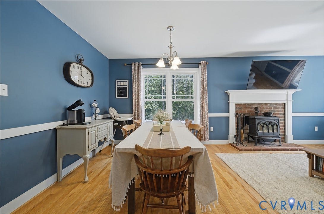700 Manchester Road, Louisa, VA 23024 Hardwood flooring, wood-burning stove with brick hearth, white mantelpiece, overhead light fixture, and window with natural light