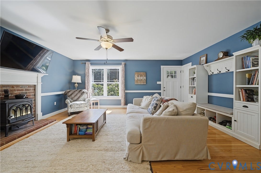 700 Manchester Road, Louisa, VA 23024 Hardwood flooring, ceiling fan, fireplace with brick surround, built-in shelving, and transom window above the entry door