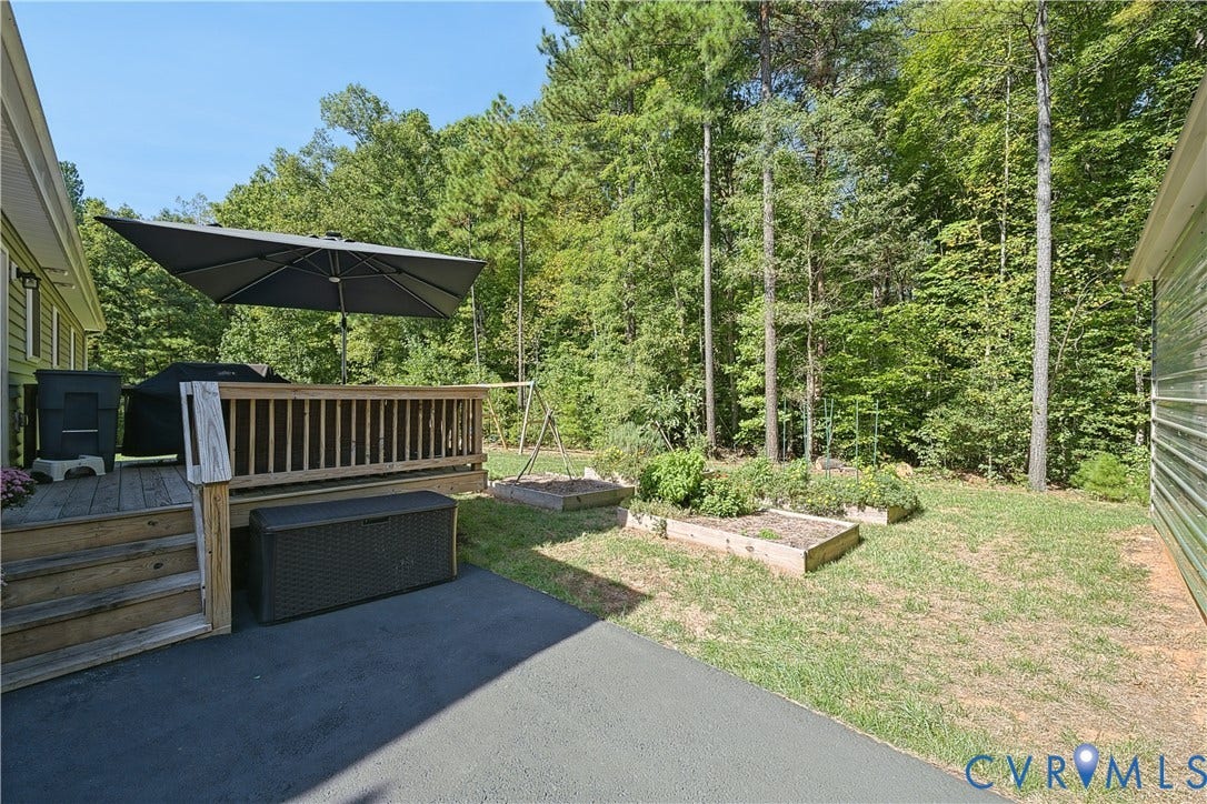 700 Manchester Road, Louisa, VA 23024 Wood deck with staircase, multiple raised garden beds, and mature perimeter trees