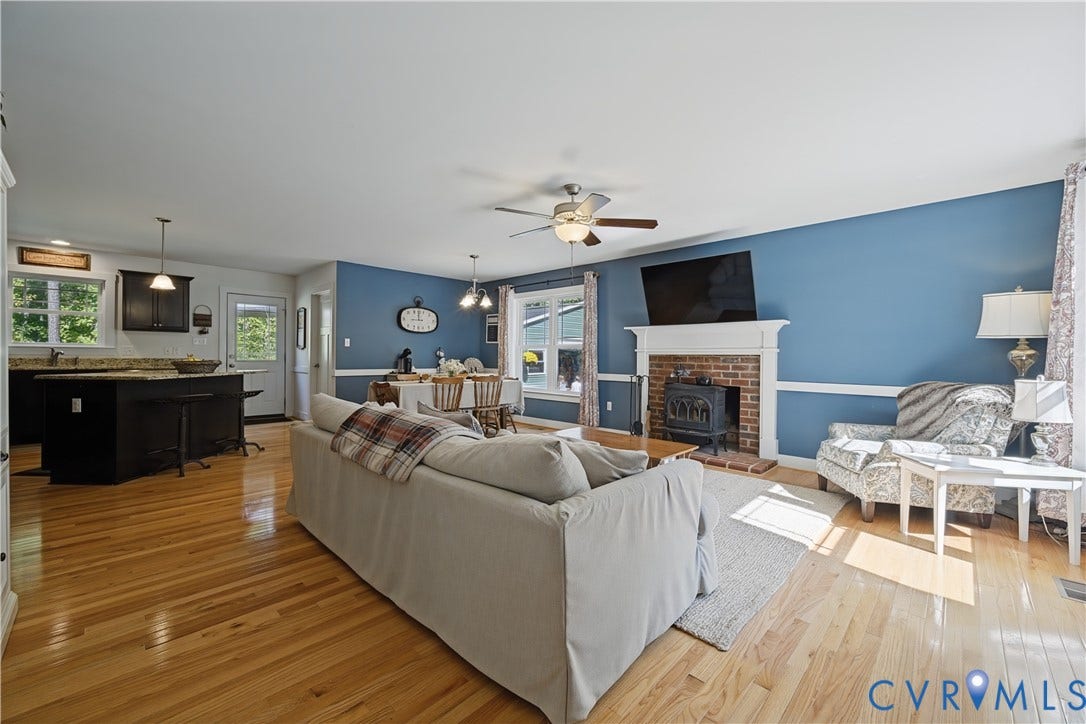 700 Manchester Road, Louisa, VA 23024 Open-concept living area with wood-finish flooring, a brick fireplace with a white mantel, and a ceiling fan