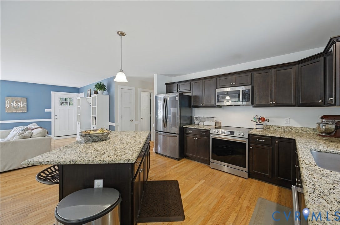 700 Manchester Road, Louisa, VA 23024 Kitchen featuring dark wood cabinetry, light-toned granite countertops, stainless steel appliances, a center island with pendant lighting, and wood-finish flooring