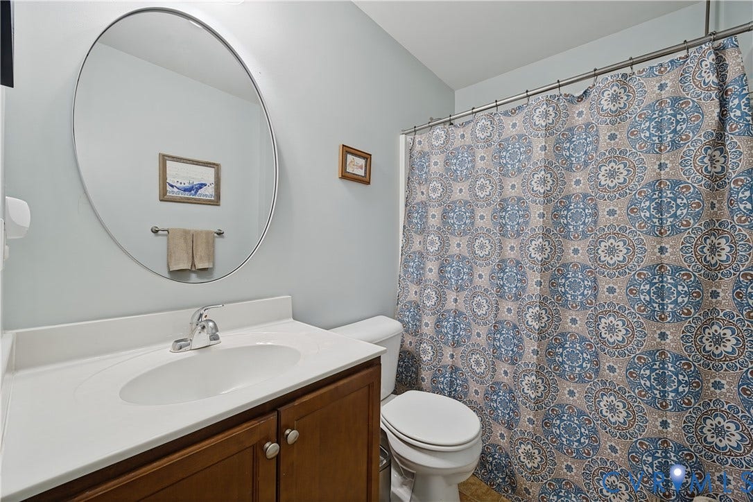 700 Manchester Road, Louisa, VA 23024 Bathroom featuring a single vanity with wood-finish cabinetry, a white countertop, and a chrome faucet