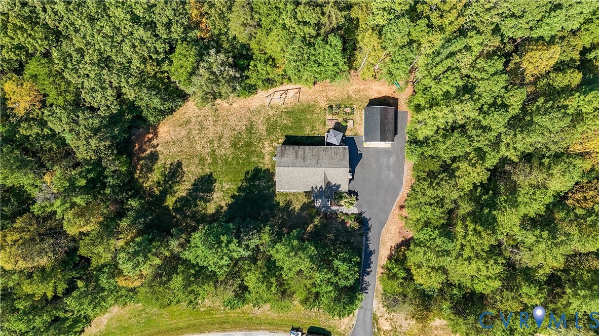 700 Manchester Road, Louisa, VA 23024 Property surrounded by mature trees, featuring a single-story structure with a gray roof, an asphalt driveway, and an additional detached structure