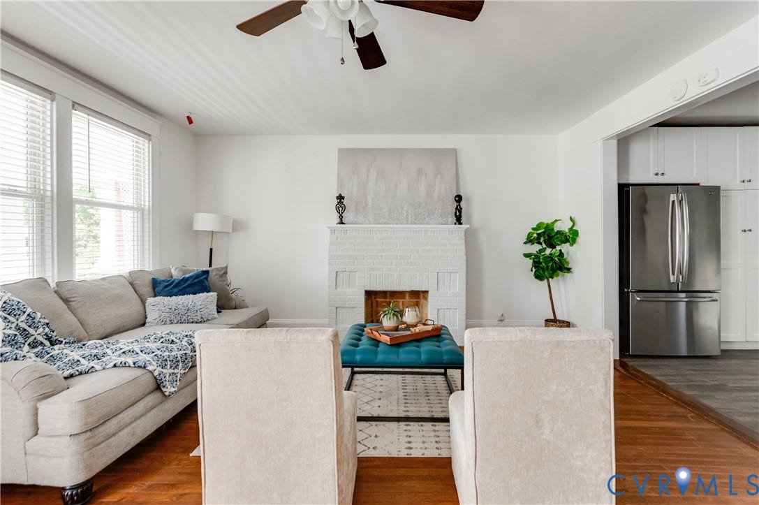 2224 Seminary Avenue, Richmond, VA 23220 Hardwood flooring, white painted brick fireplace, ceiling fan, natural light from multiple windows, and a stainless steel refrigerator