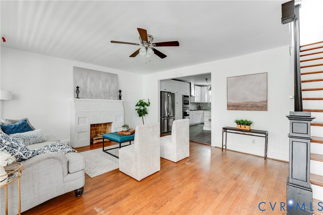 2224 Seminary Avenue, Richmond, VA 23220 Hardwood flooring, painted brick fireplace, a ceiling fan, a staircase with painted newel posts, and an arched opening to the kitchen