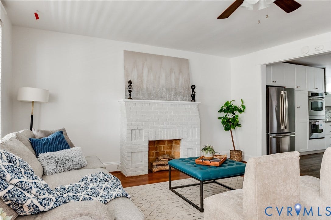 2224 Seminary Avenue, Richmond, VA 23220 Painted brick fireplace with hearth, wood-finish flooring, white walls, and a ceiling fan with wood-finish blades