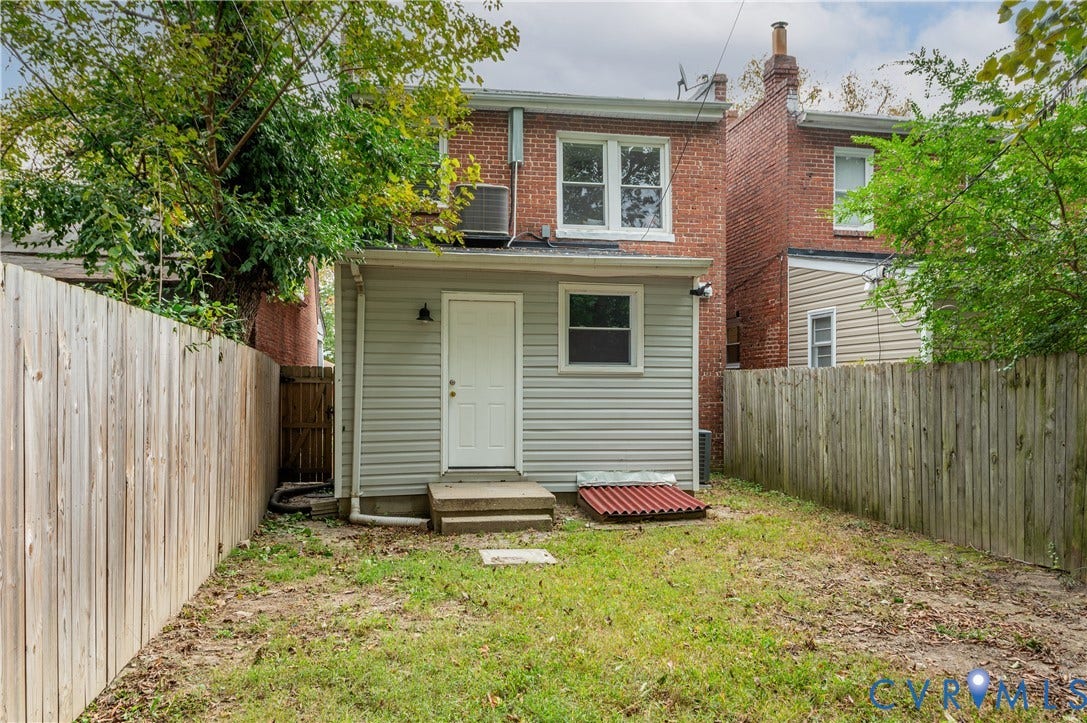 2224 Seminary Avenue, Richmond, VA 23220 Rear exterior featuring a privacy fence, a white entry door, and a ground-level window
