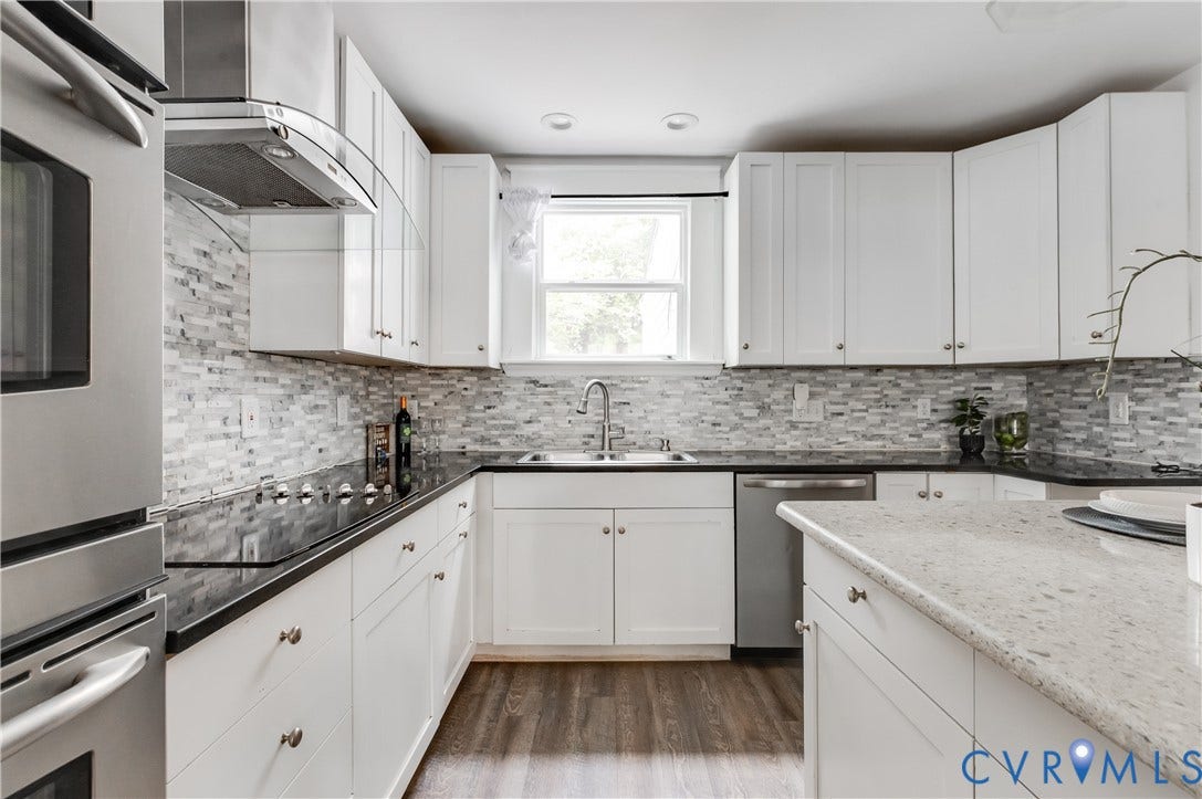 2224 Seminary Avenue, Richmond, VA 23220 White cabinetry, mosaic tile backsplash, black countertops, stainless steel appliances, and wood-finish flooring