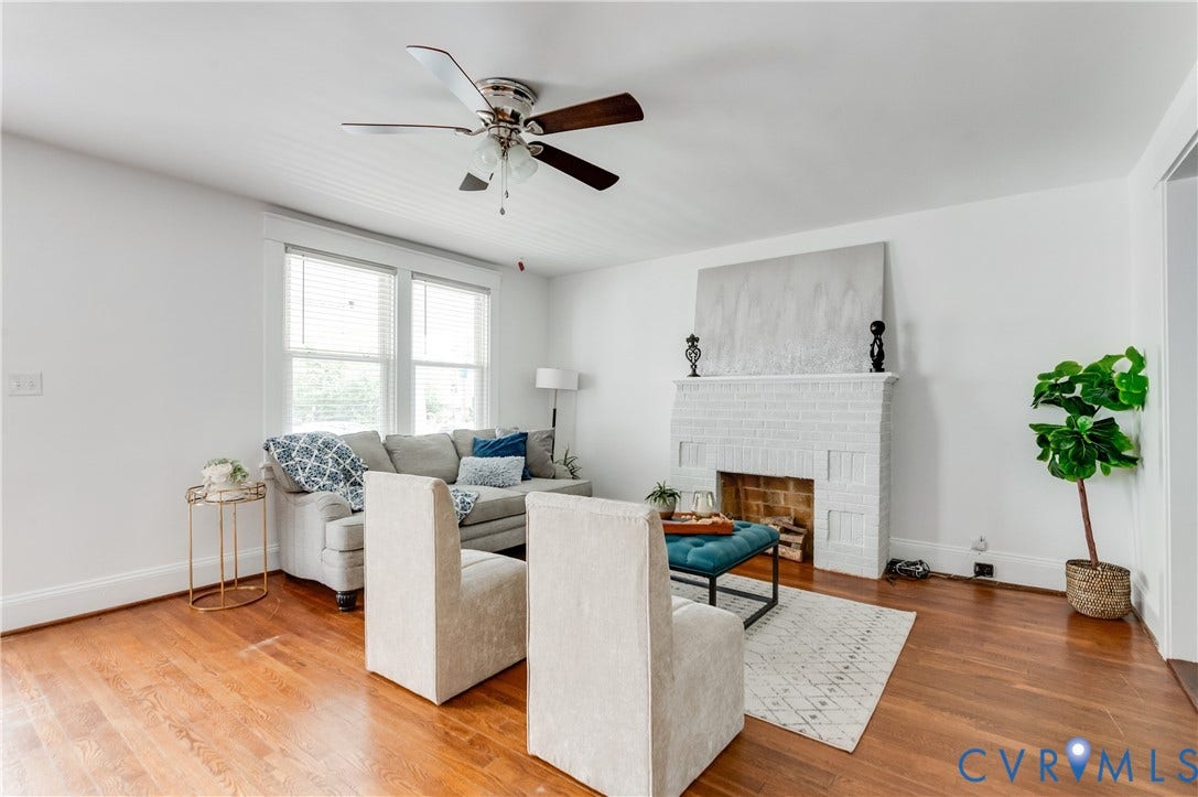 2224 Seminary Avenue, Richmond, VA 23220 Hardwood flooring, painted brick fireplace, ceiling fan, multiple windows, and white walls