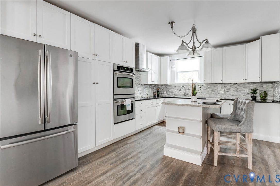 2224 Seminary Avenue, Richmond, VA 23220 Kitchen featuring wood-finish flooring, white cabinetry, stainless steel appliances, a center island with a built-in counter, and a tile backsplash