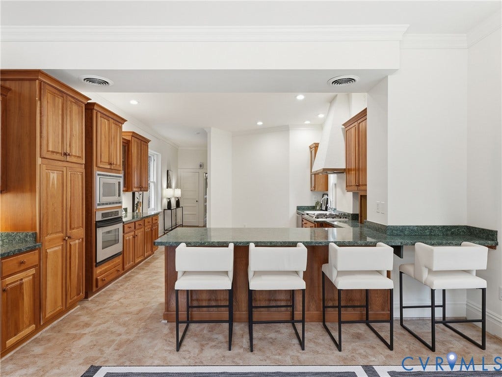 1901 Hanover Avenue, Fan, Richmond, VA 23220 Expansive kitchen featuring wood cabinetry, integrated stainless steel appliances, a generous island with seating, and a matching stone countertop