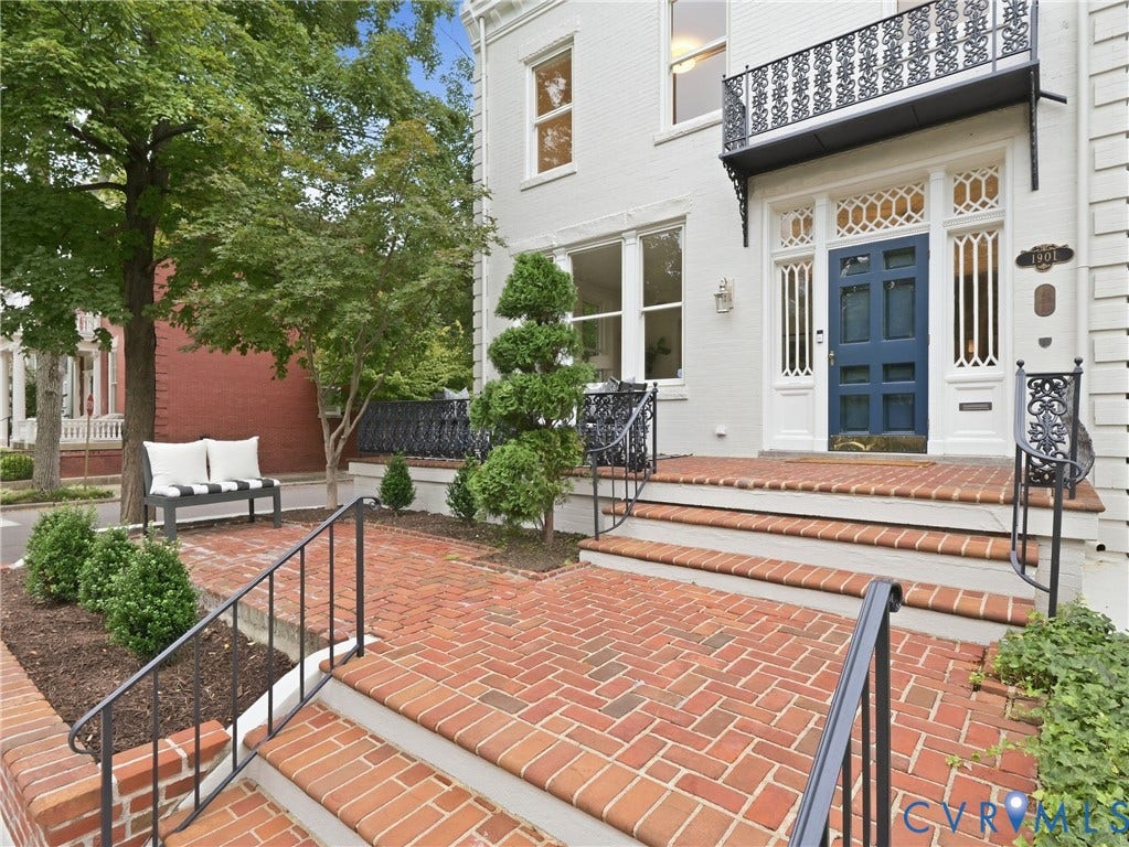 1901 Hanover Avenue, Fan, Richmond, VA 23220 White facade with a blue paneled entry door, ornate iron balcony, brick paver courtyard, and wrought iron railings