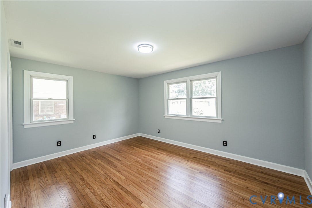 1724 Alaska Drive, Richmond, VA 23224 Hardwood flooring, light blue wall paint, two windows with white trim, and a flush mount ceiling light