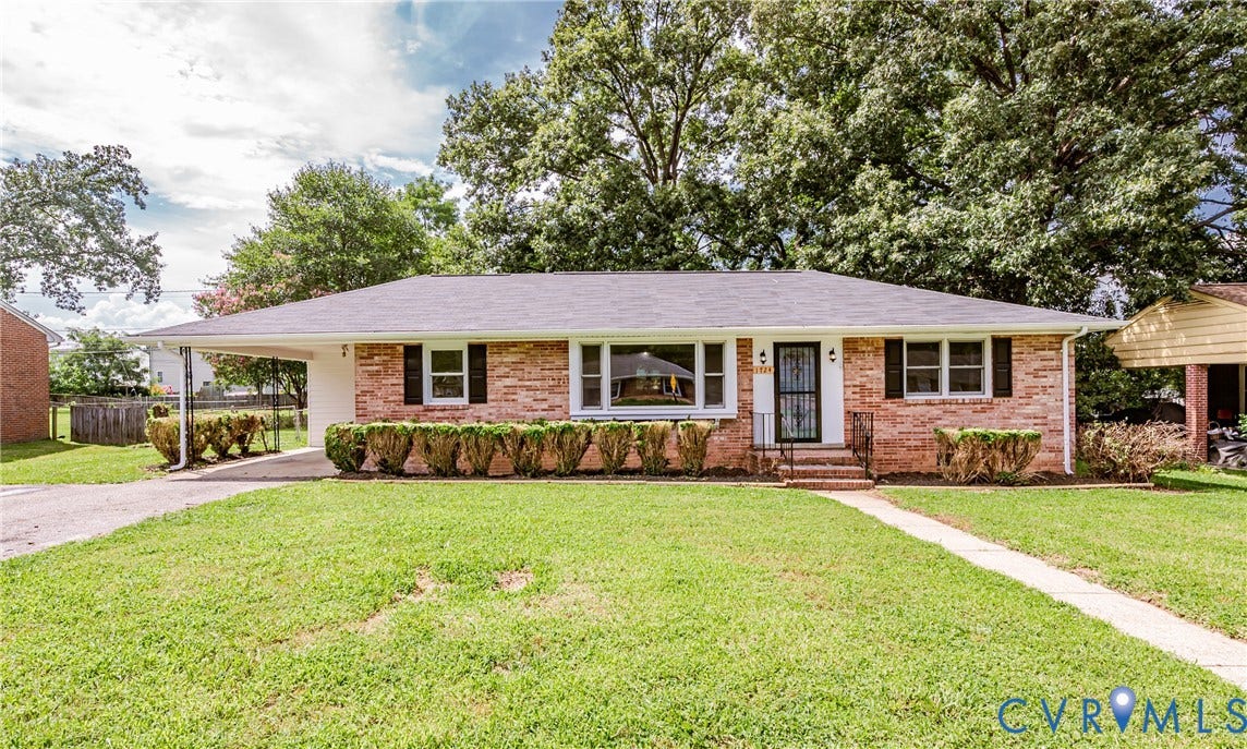 1724 Alaska Drive, Richmond, VA 23224 Brick exterior with a covered carport, mature trees, and established landscaping