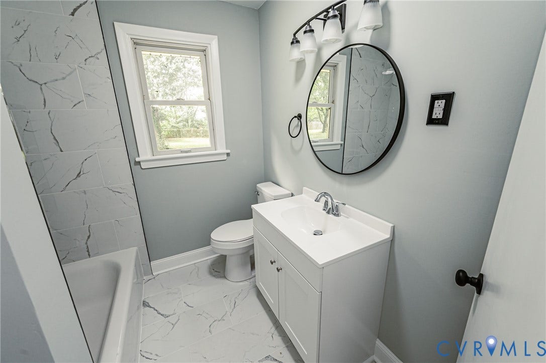 1724 Alaska Drive, Richmond, VA 23224 Bathroom featuring a white vanity with integrated sink, chrome faucet, round mirror, and a five-light fixture