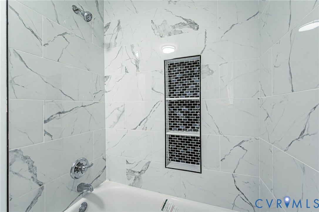 1724 Alaska Drive, Richmond, VA 23224 Bathtub with marble-look tile surround, mosaic tiled shower niche, and chrome fixtures