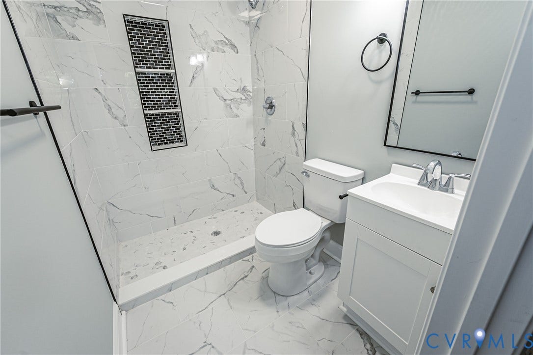 1724 Alaska Drive, Richmond, VA 23224 Shower featuring marble-look tile walls, a mosaic tile niche, and a contrasting black shower rod
