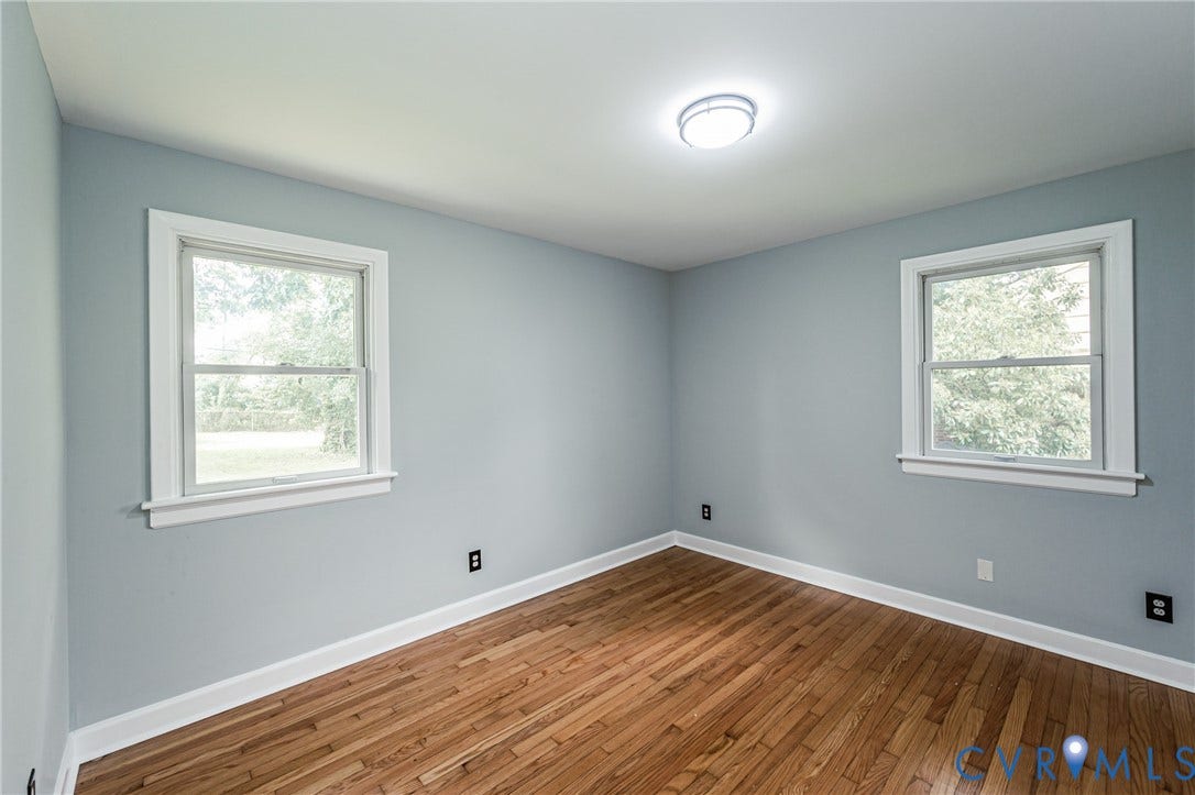 1724 Alaska Drive, Richmond, VA 23224 Wood-finish flooring, two sash windows with white trim, light blue wall paint, and a flush mount ceiling light