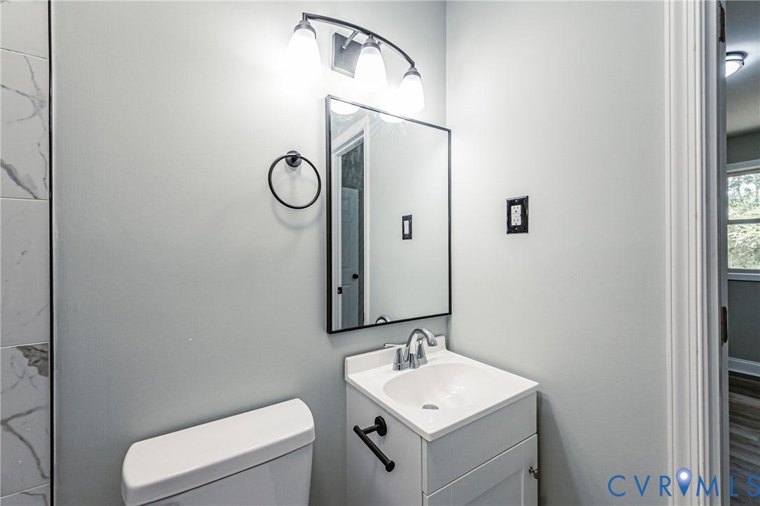 1724 Alaska Drive, Richmond, VA 23224 White vanity with integrated sink, black-framed mirror, and chrome faucet