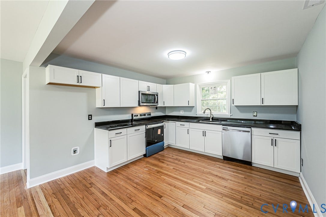 1724 Alaska Drive, Richmond, VA 23224 Kitchen featuring wood-finish flooring, white cabinetry with dark hardware, dark countertops, and stainless steel appliances