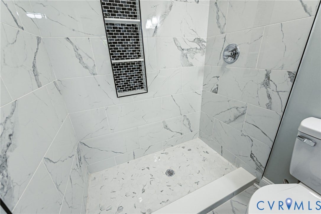 1724 Alaska Drive, Richmond, VA 23224 Walk-in shower featuring large format white tiled walls with gray veining, a mosaic tile shower niche, a chrome shower fixture, and a mosaic tiled shower floor