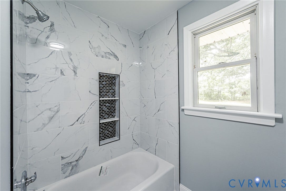 1724 Alaska Drive, Richmond, VA 23224 Bathtub with chrome fixtures, large format tile surround, and recessed shelving with mosaic tile