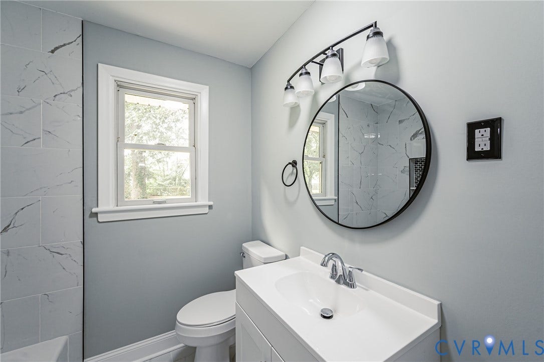 1724 Alaska Drive, Richmond, VA 23224 Bathroom featuring a white vanity with integrated sink, chrome faucet, and a round black-framed mirror