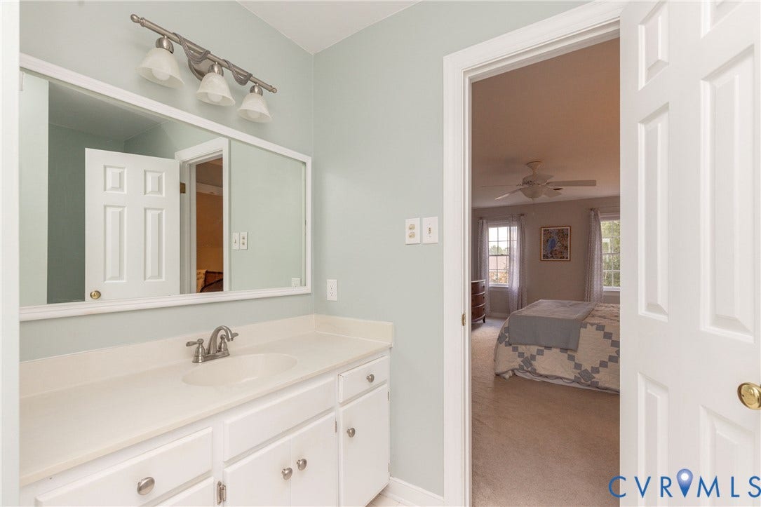 2120 Willowick Lane, Henrico, VA 23238 White vanity with a single basin sink and brushed nickel faucet, large framed mirror, and three-light vanity bar fixture