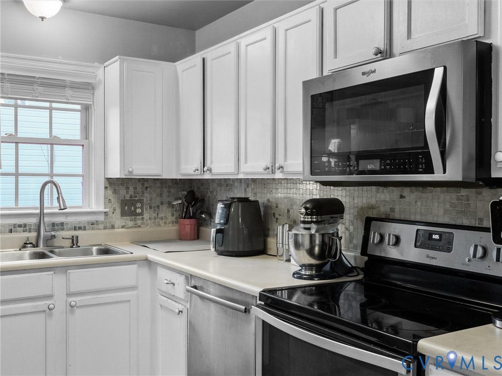 6507 Fairpines Road, North Chesterfield, VA 23234 White cabinetry with brushed nickel hardware, stainless steel appliances, mosaic tile backsplash, and a double basin sink with a gooseneck faucet