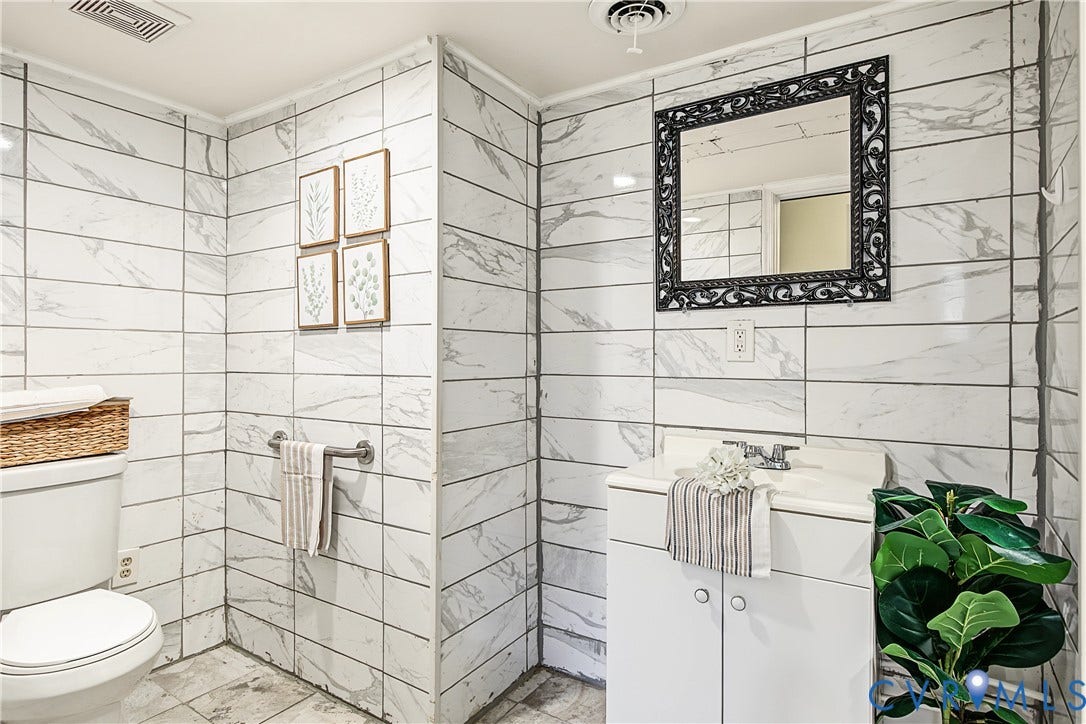 13310 Gladehill Road, Hidden Valley Estates, Chesterfield, VA 23831 White tiled walls and floor, white toilet, white vanity with integrated sink, and an ornate framed mirror