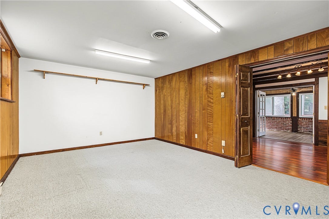 13310 Gladehill Road, Hidden Valley Estates, Chesterfield, VA 23831 Hardwood paneling, light carpet, overhead fluorescent lighting, and a doorway opening to a sunroom with brick accents and a wood-finish floor