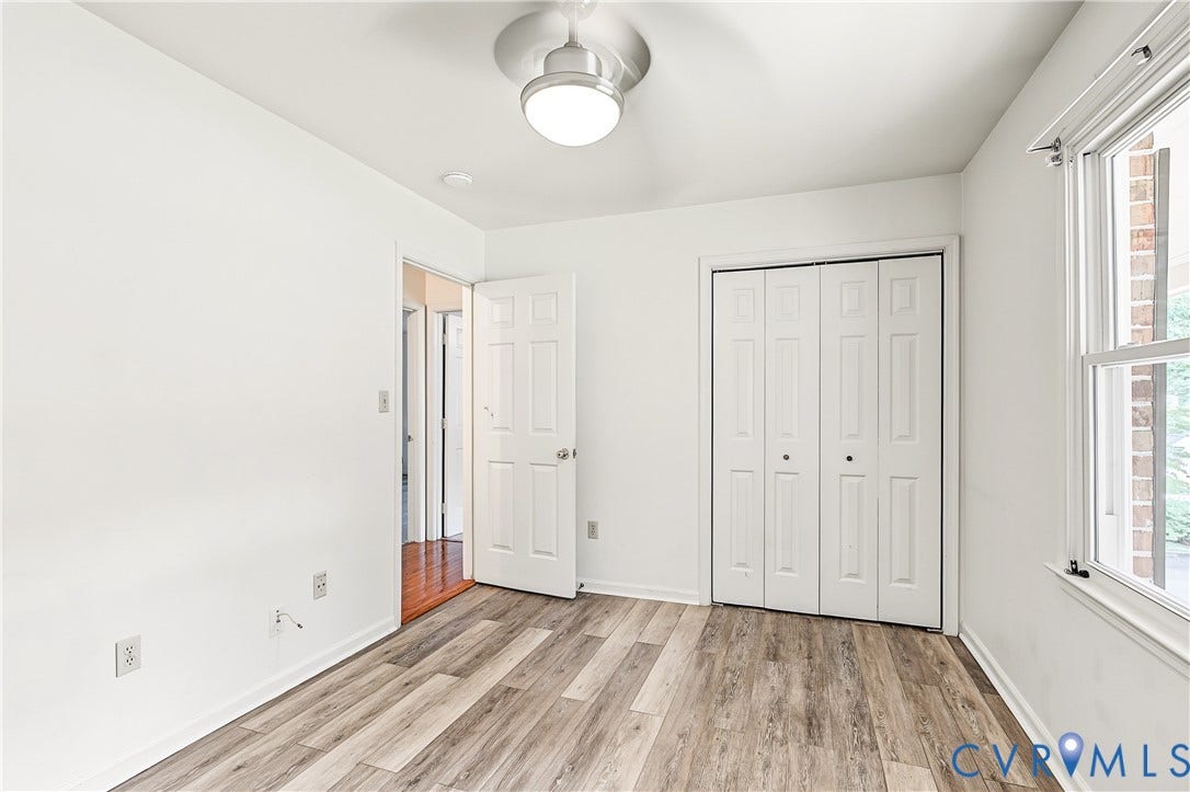 13310 Gladehill Road, Hidden Valley Estates, Chesterfield, VA 23831 Wood-finish flooring, white bi-fold closet doors, white paneled interior door, ceiling-mounted light fixture with fan, and a window with white trim