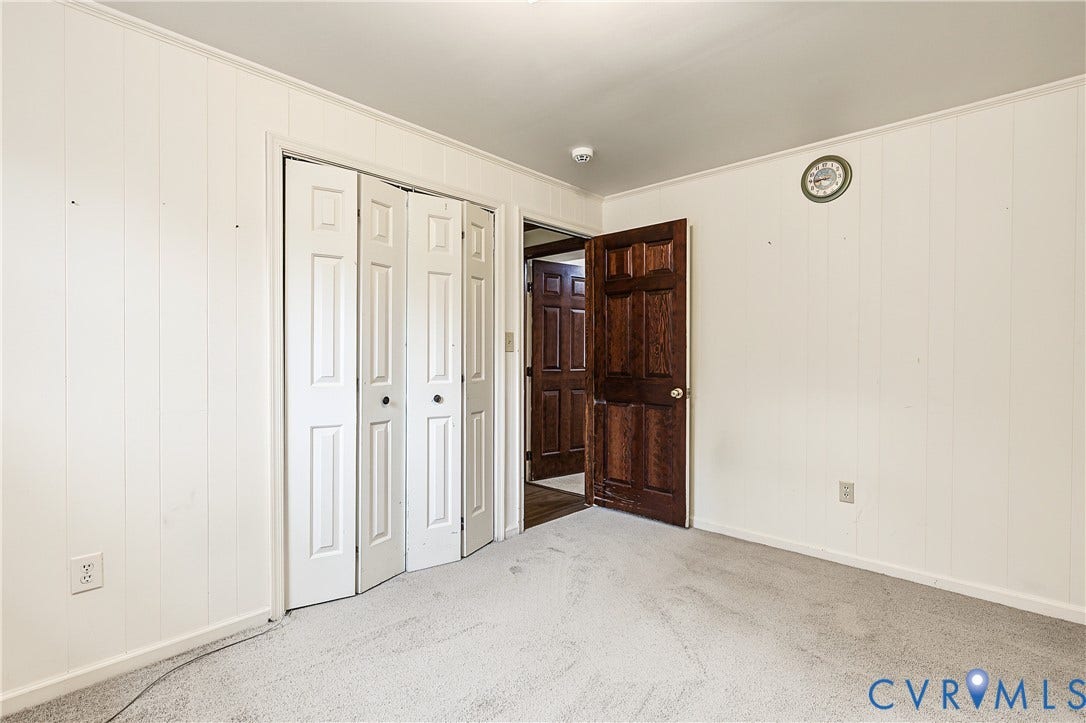 13310 Gladehill Road, Hidden Valley Estates, Chesterfield, VA 23831 Light-colored wall paneling, white bi-fold closet doors, a dark wood-finish interior door, and light-toned carpeting